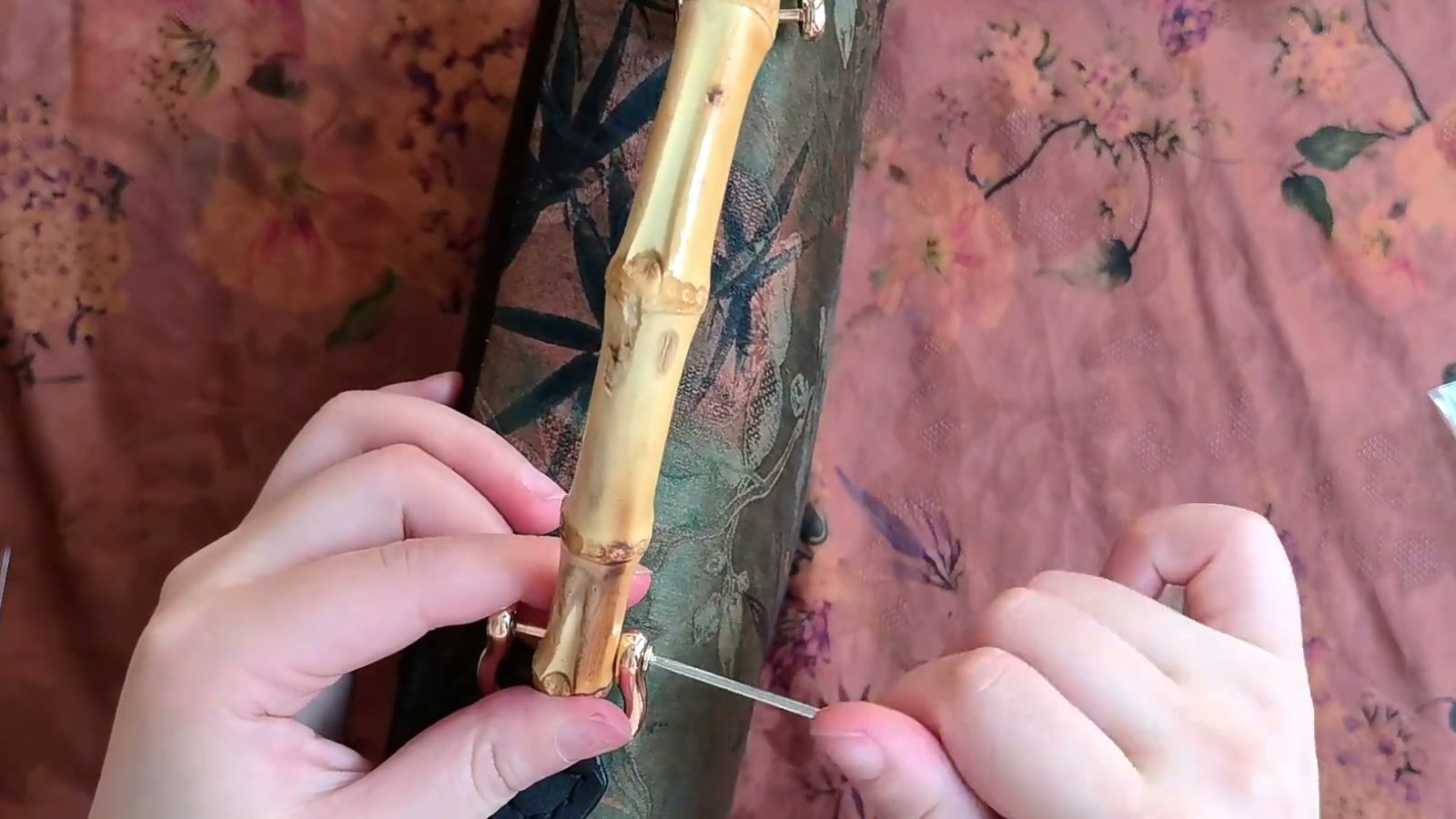 One end of the bamboo handle sits inside a gold U-ring while a small screwdriver is positioned to secure the crossbar screw