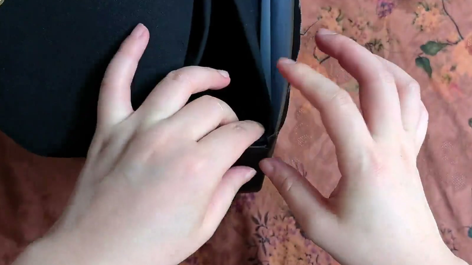 The raw outer-fabric and lining edges are folded inward between the layers while two hands smooth the top opening