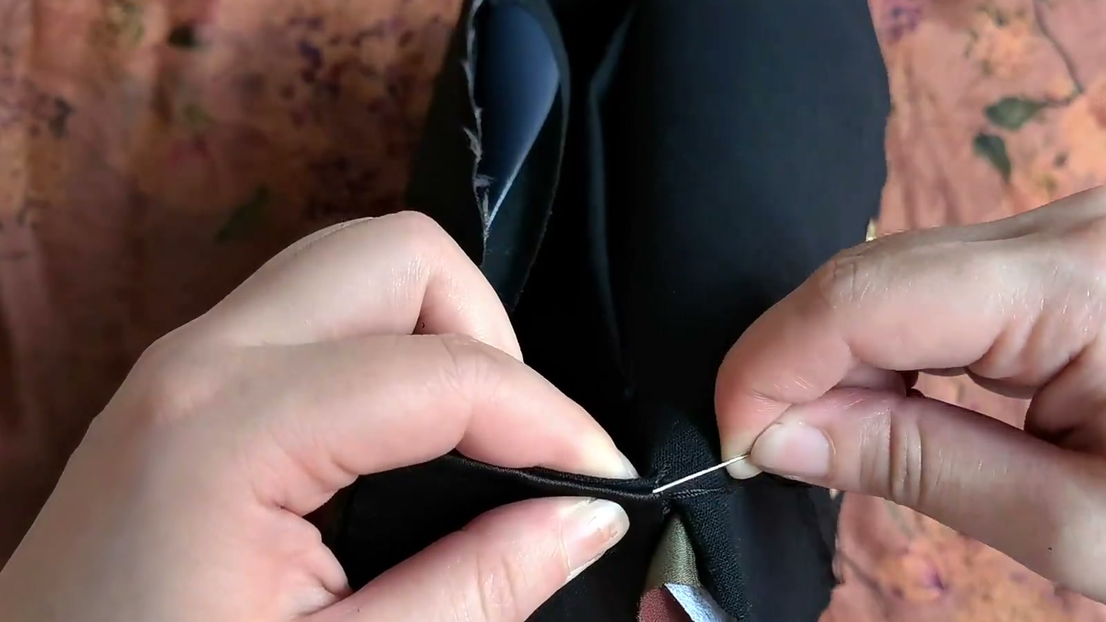 A hand needle alternates between the folded outer-fabric and lining edges so the thread disappears between the layers
