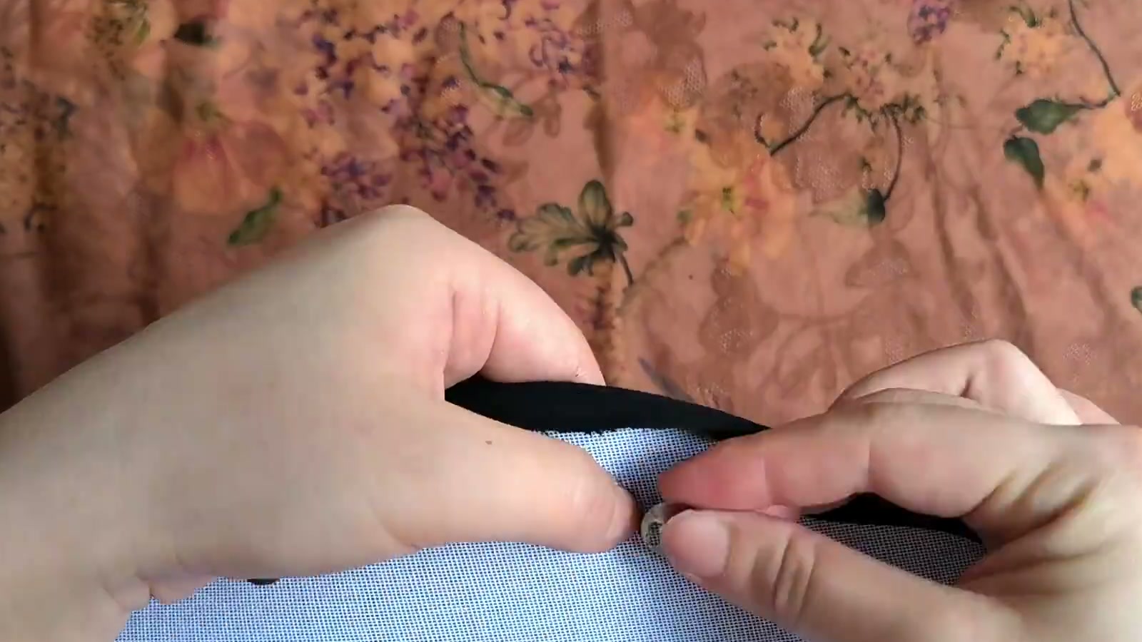 Fingers pass one magnetic-snap prong set through a washer on the interfacing side of the black lining and bend the prongs outward