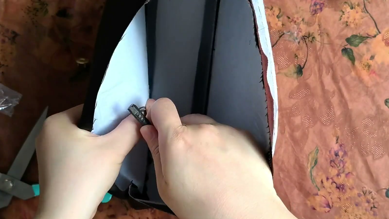 Fingers pass the magnetic-snap prongs through a washer on the batting side and bend both prongs outward