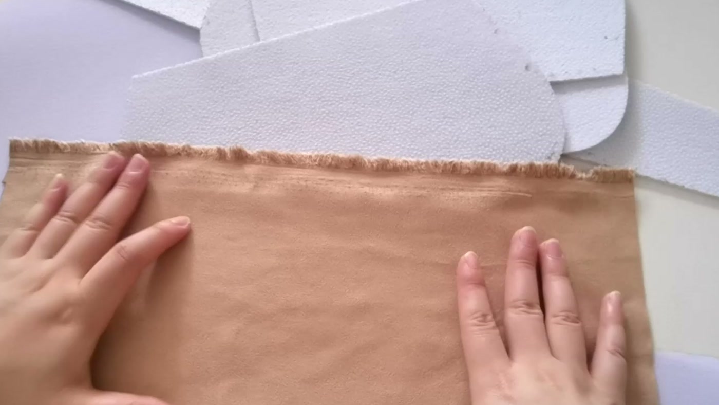 Two hands smoothing the fabric and stabilizer layers flat before pressing